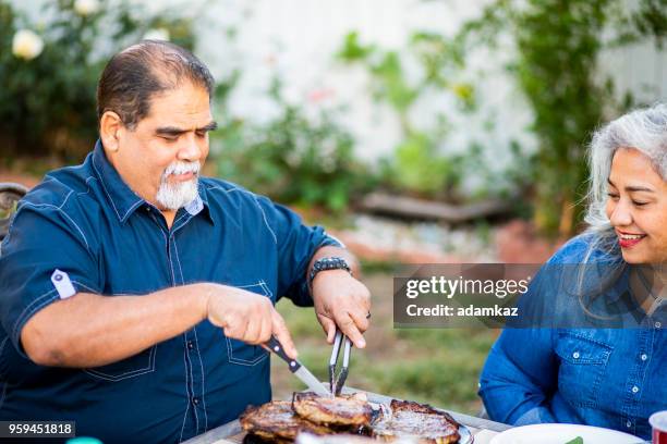 senior mexican man serving steaks at dinner - fat mexican man stock pictures, royalty-free photos & images