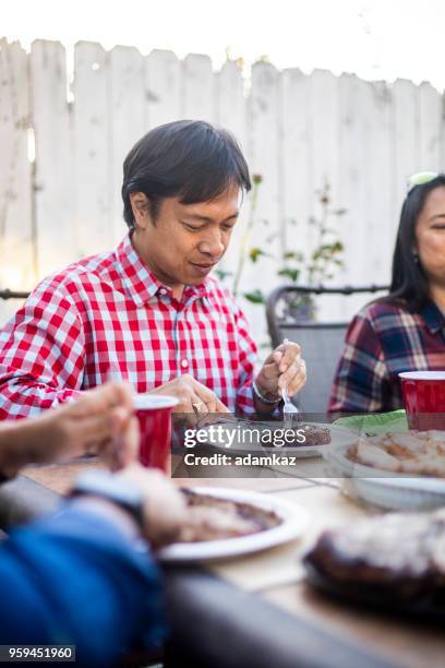 filipino man enjoys steak at outdoor dinner - filipino family eating stock pictures, royalty-free photos & images