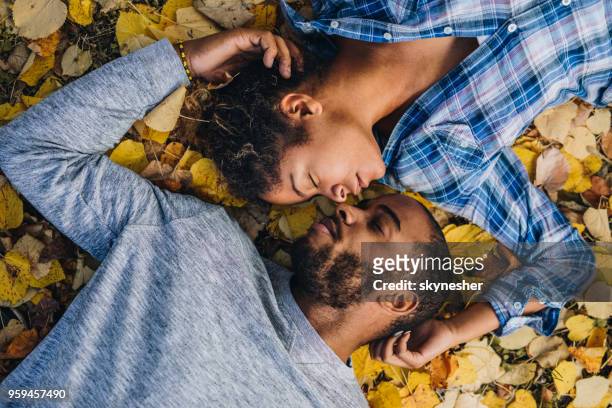 avant l’avis du couple noir au repos avec les yeux fermés en automne feuilles. - allongé sur le dos photos et images de collection