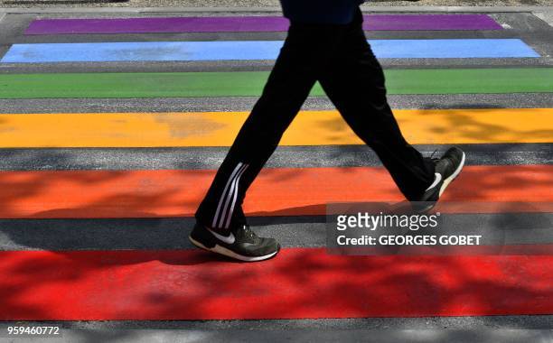 Person uses a road crossing adorned with the colours of the rainbow in Perigueux on May 17, 2018 as part of events marking International Day against...
