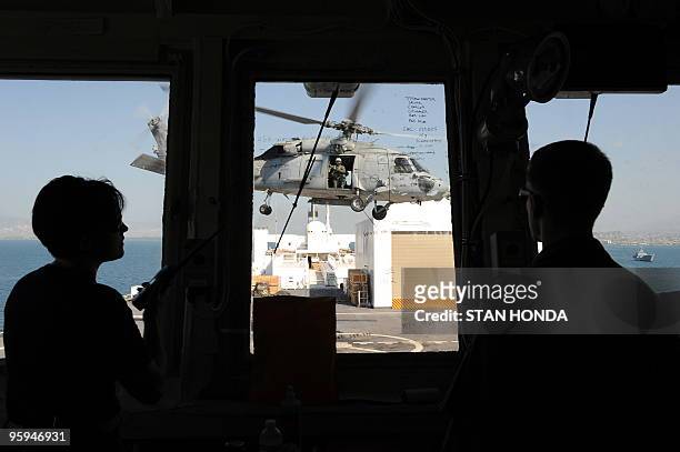 Navy helicopter prepares to land aboard the USNS Comfort hospital ship as seen from the flight control deck on 22 January, 2010 in the harbor off...