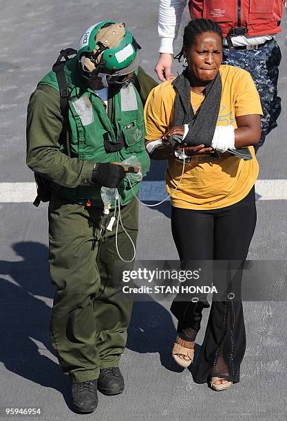 Hatian earthquake victim is escorted off a medical helicopter aboard the USNS Comfort hospital ship on 22 January, 2010 in the harbor off...