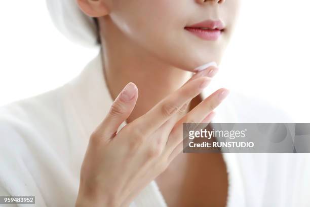 woman applying cream to face - 若い女性 日本人 顔 ストックフォトと画像