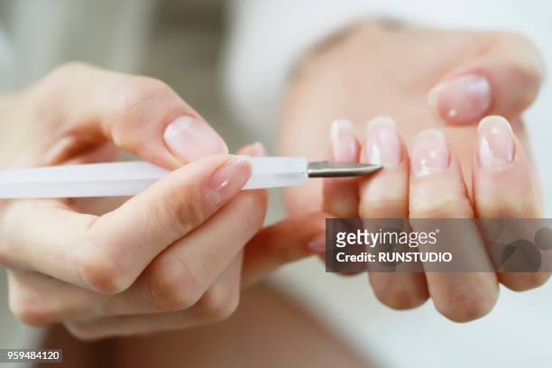 woman using cuticle pusher - nagelhaut stock-fotos und bilder