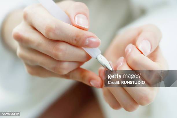 woman using cuticle pusher - nagelhaut stock-fotos und bilder