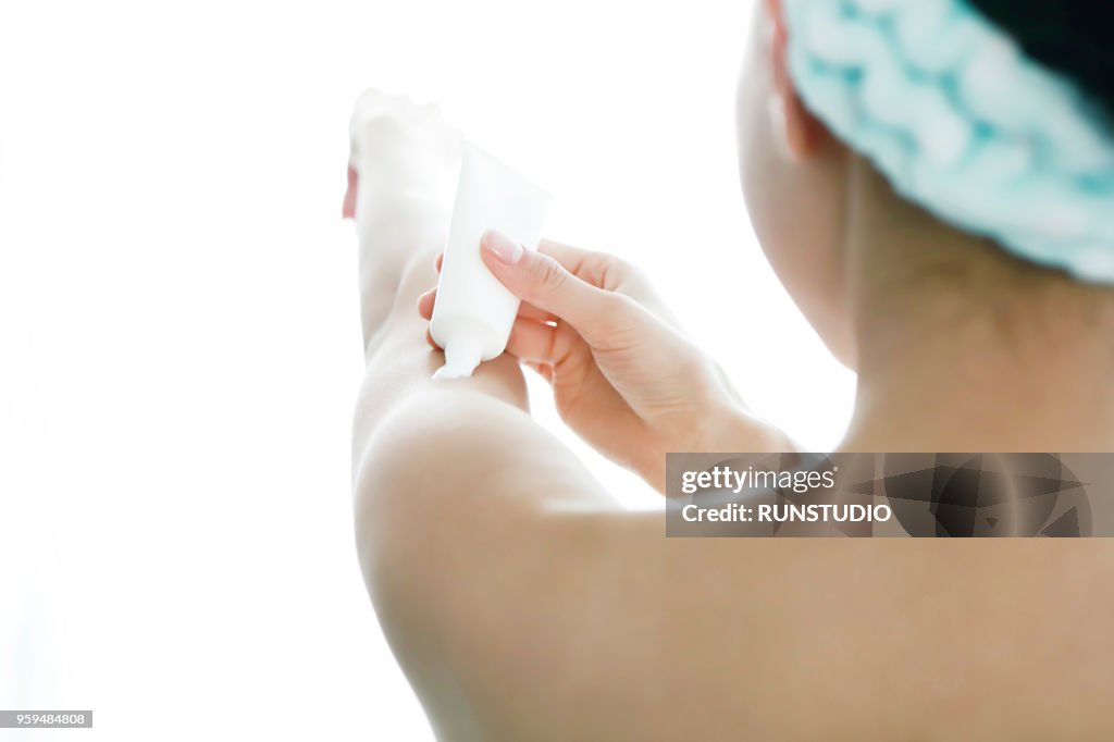 Woman applying moisturizer on arm