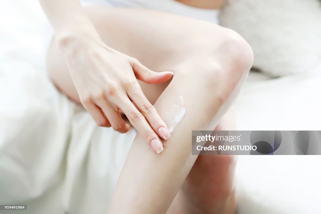 Woman applying body lotion on leg