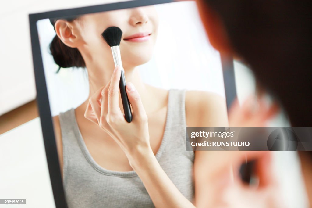 Woman applying blush in mirror