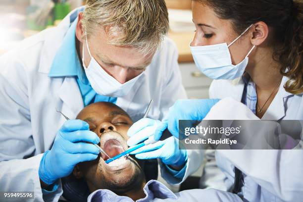 tandarts werken op patiënt tanden, assistent permanent door - dental explorer stockfoto's en -beelden
