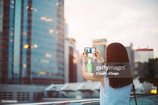 woman photographing with smartphone in central business district of hong kong - 背中 手 ストックフォトと画像
