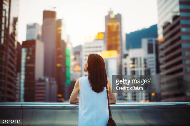 rear view of woman looking up to sky with smile on a fresh bright morning in city - asian woman smiling sunrise stock-fotos und bilder