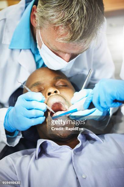 dentist working on patient's teeth - suction tube stock pictures, royalty-free photos & images