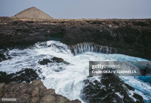 Natural pool in the basaltic rocks of Buracona Bay, in the background Mount Leste, Ilha do Sal, Cape Verde.