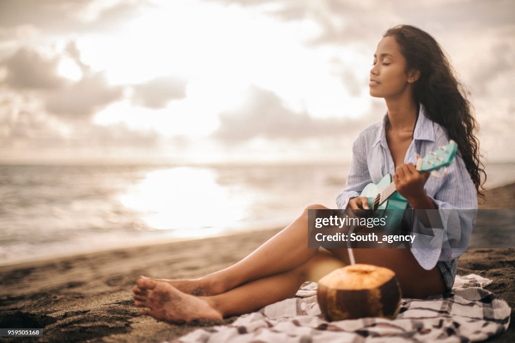 在海灘的婦女演奏四弦琴