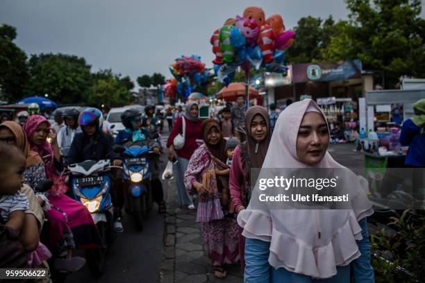 Muslim women walk as prepare for iftar on the first day of the holy month of Ramadan at the yard of Grand mosque on May 17, 2018 in Surabaya,...