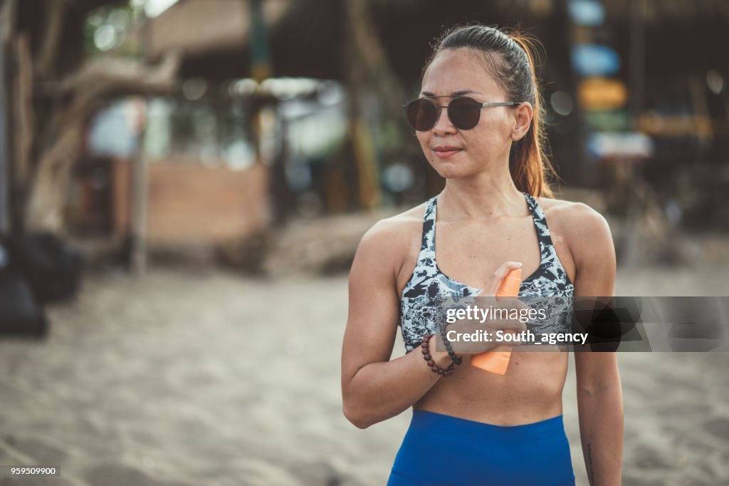 Woman athlete using sun cream at the beach