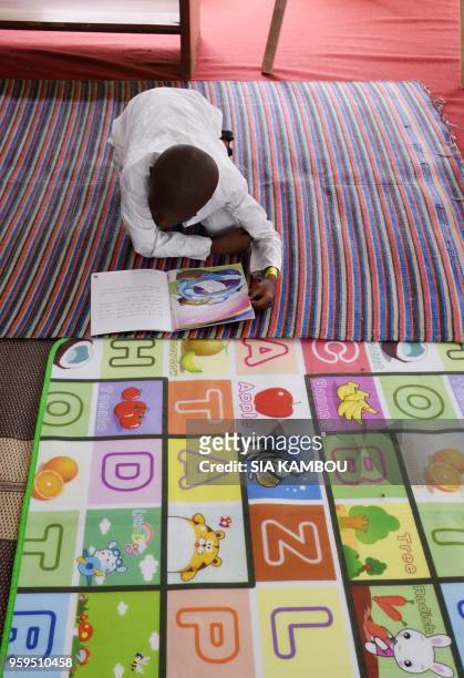 Young boy reads a book during the International Book Fair at the Palace of Culture in Abidjan, on May 17, 2018.