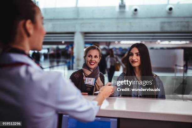 women at airport doing check-in at airline counter - airline service stock pictures, royalty-free photos & images