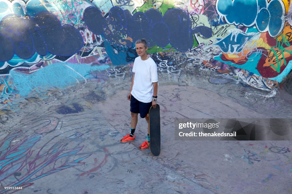 Woman standing in skate park with skateboard