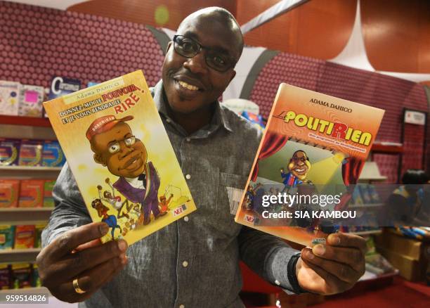 Ivorian actor and humorist Adama Dolo, aka Adama Dahico, poses with some of his books during the International Book Fair at the Palace of Culture in...