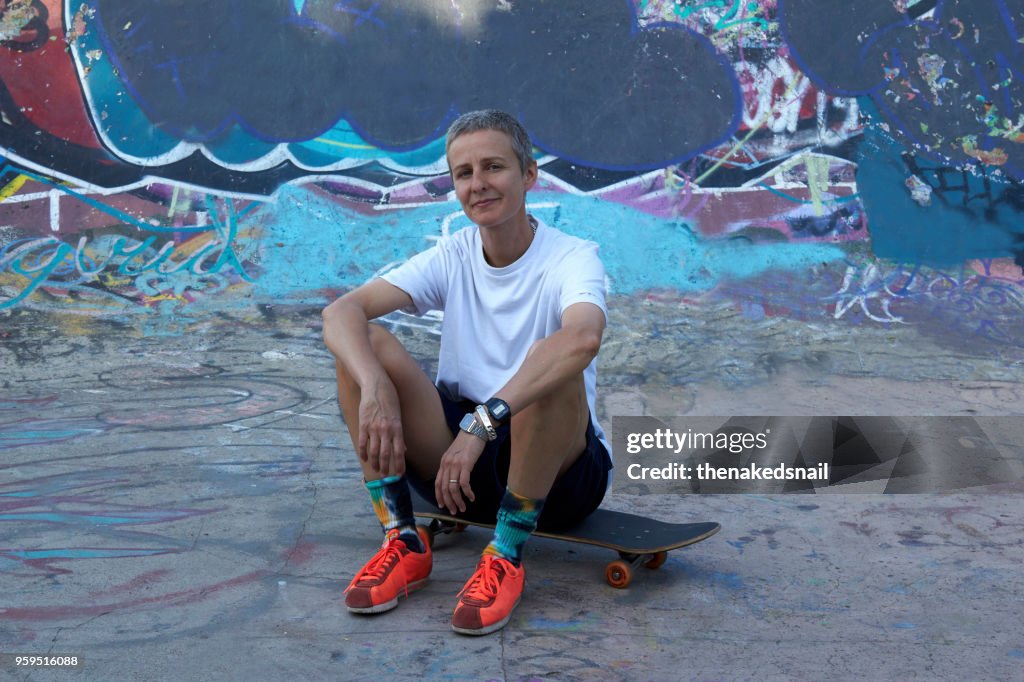 Portrait of woman sitting on skate board looking to camera