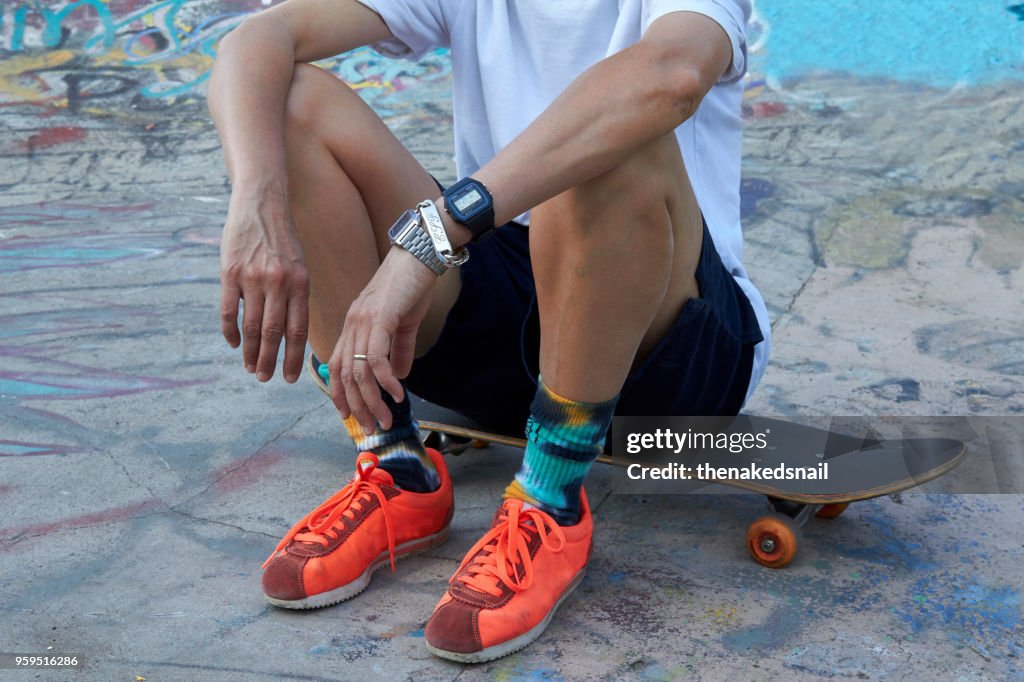 Crop of woman sitting on skateboard in skateboard park