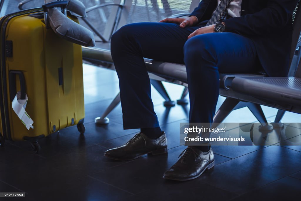 Businessman with suitcase waiting at airport departure area