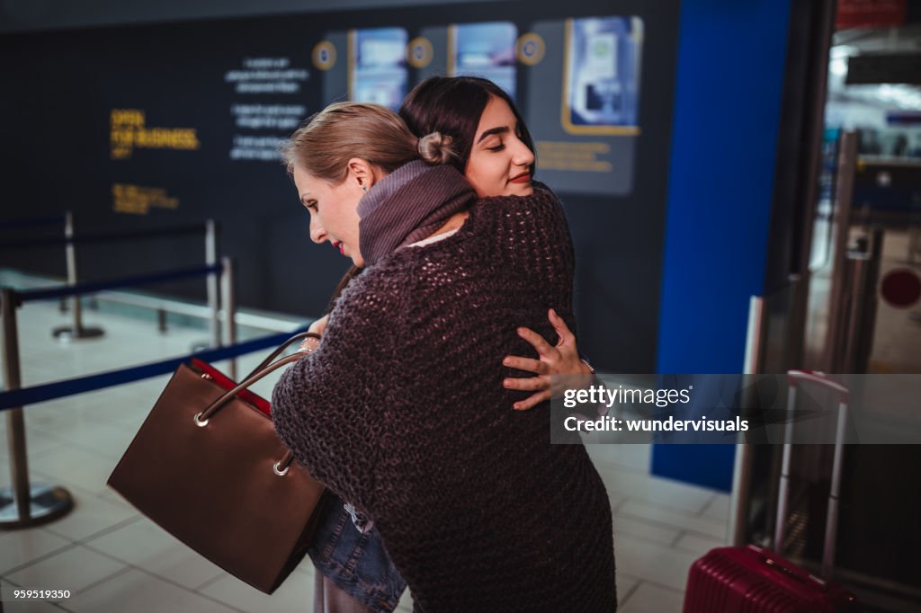 Mother embracing teenage daughter ready for departure at airport