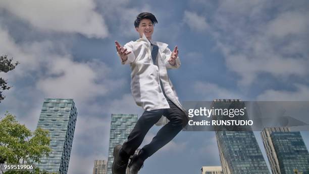 portrait of smiling doctor jumping - doctor leaping stock pictures, royalty-free photos & images