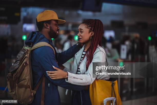 young couple embracing and saying emotional farewell at airport - couple airport stock pictures, royalty-free photos & images