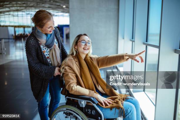 giovane donna disabile su sedia a rotelle e madre in attesa in aeroporto - sedia a rotelle foto e immagini stock