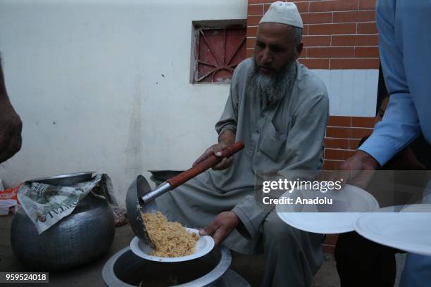 Muslim man fills a plastic plate within the iftar dinner preparations on the first day of holy Islamic month of Ramadan in Islamabad, Pakistan on May...
