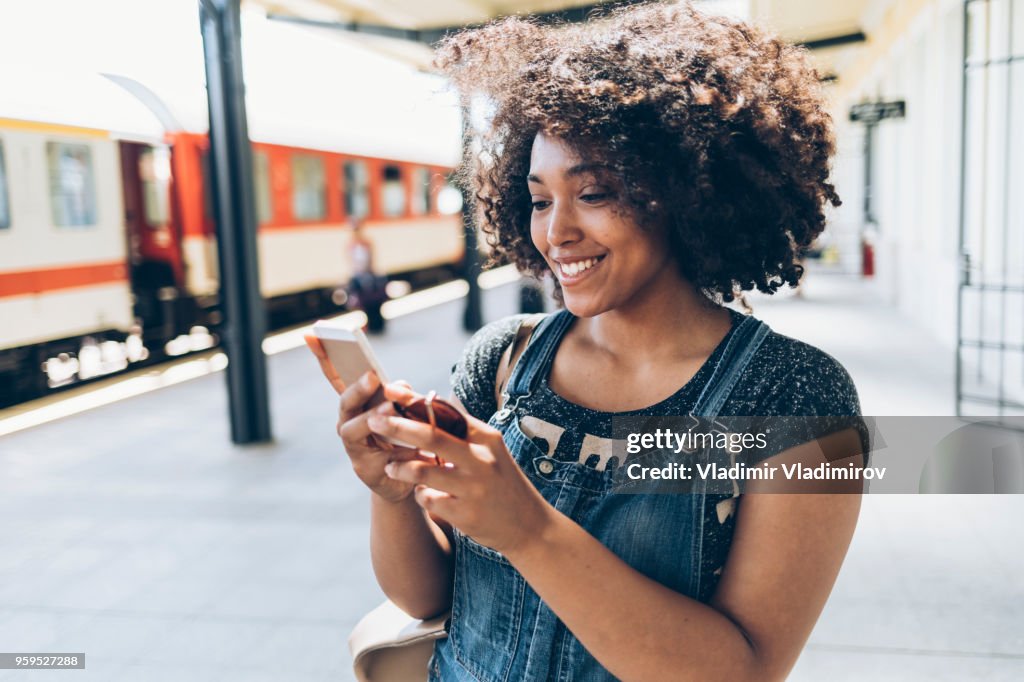 Smiling woman using smart phone on station