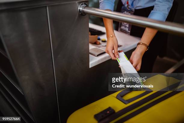 dipendente del banco del check-in dell'aeroporto che allega l'etichetta sui bagagli - bagagli foto e immagini stock