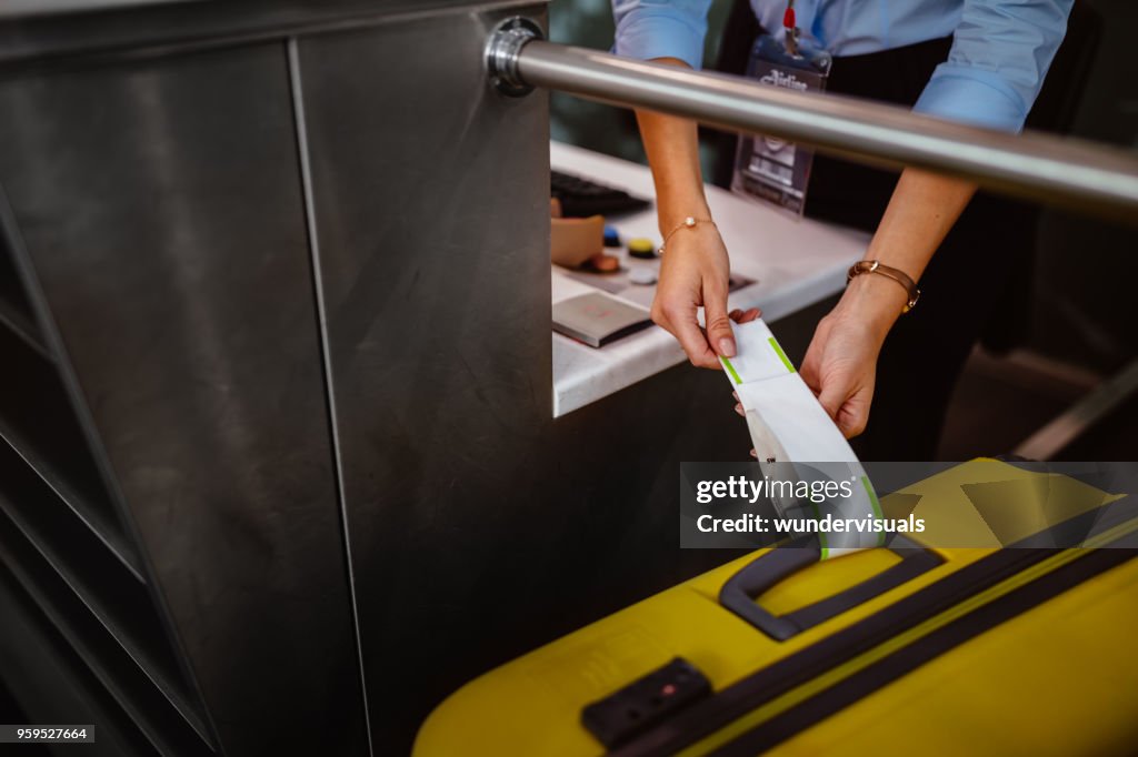 Airport check-in counter employee attaching tag on luggage