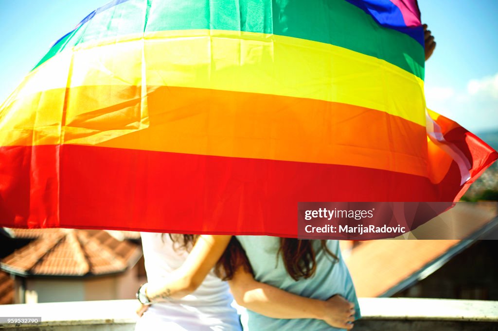 LGBT-lesbisches paar Momente Glück Konzept. Regenbogenfahne halten im freien