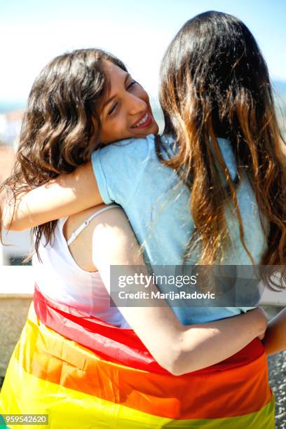 lgbt-lesbisches paar momente glück konzept. regenbogenfahne halten im freien - marijaradovic stock-fotos und bilder