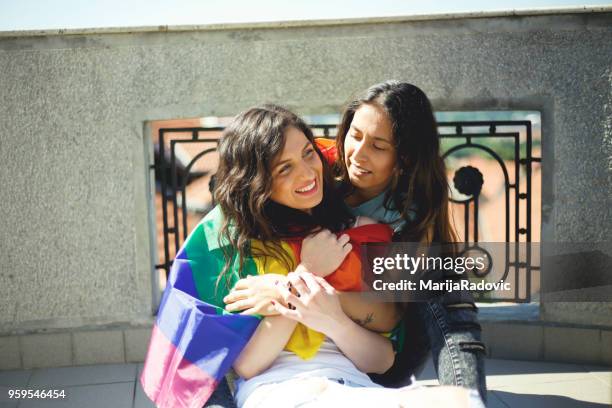 lgbt-lesbisches paar momente glück konzept. regenbogenfahne halten im freien - marijaradovic stock-fotos und bilder