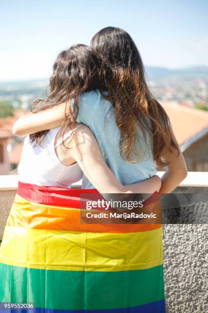 lgbt-lesbisches paar momente glück konzept. regenbogenfahne halten im freien - marijaradovic stock-fotos und bilder