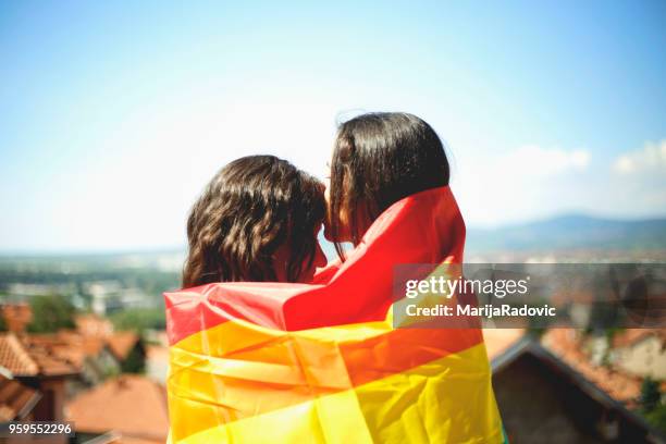 lgbt-lesbisches paar momente glück konzept. regenbogenfahne halten im freien - marijaradovic stock-fotos und bilder