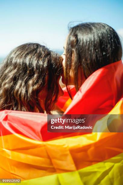 lgbt-lesbisches paar momente glück konzept. regenbogenfahne halten im freien - marijaradovic stock-fotos und bilder