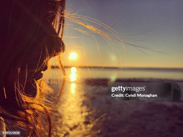 girl with windswept hair at sunset - girl beach sunset stock-fotos und bilder