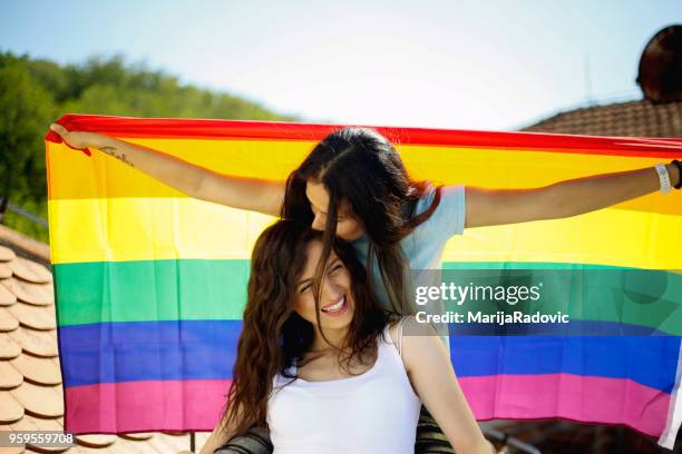 lgbt-lesbisches paar momente glück konzept. regenbogenfahne halten im freien - marijaradovic stock-fotos und bilder