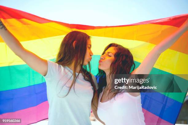 lgbt-lesbisches paar momente glück konzept. regenbogenfahne halten im freien - marijaradovic stock-fotos und bilder