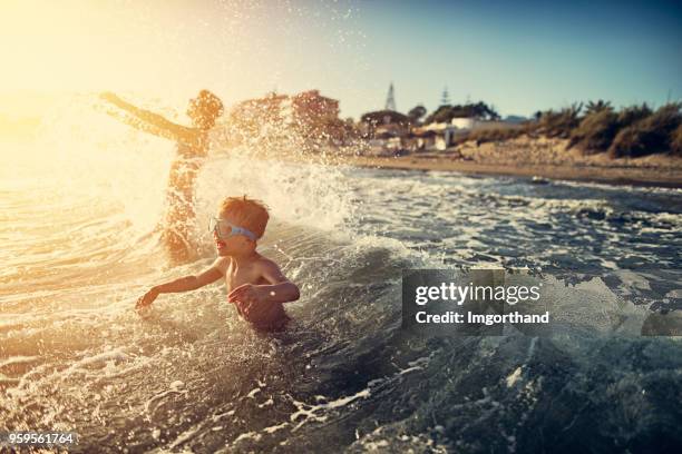 broer en zus spetteren in de zomer zee - life event stockfoto's en -beelden