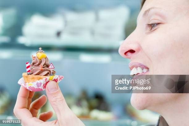 jonge vrouw houdt weinig gebak met miniaturen in een patisserie - pjphoto69 stockfoto's en -beelden