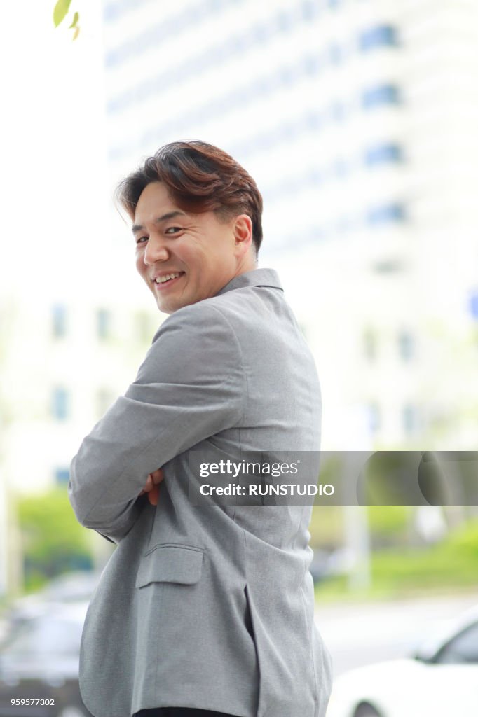 Middle aged businessman with arms folded outside office building