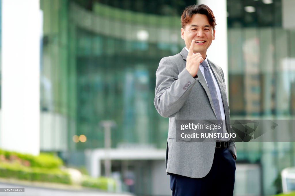 Middle aged businessman pointing finger outdoors