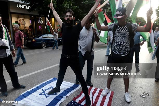 Palestinian protester stands on USA and an Israeli flags in front of the US consulate during a demonstration on May 17 to denounce the bloodshed...