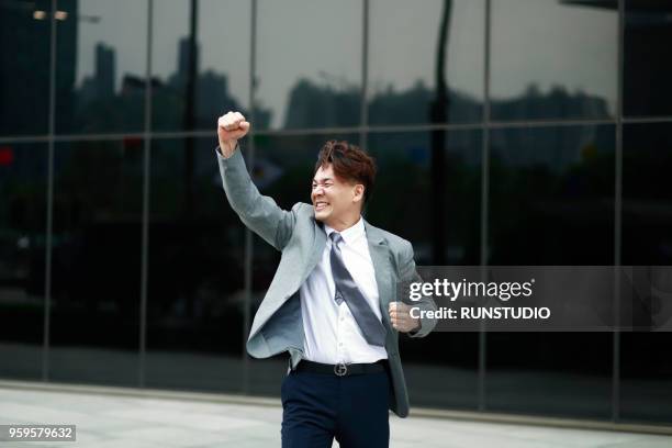 middle aged businessman punching air outdoors - faust in die luft stoßen stock-fotos und bilder